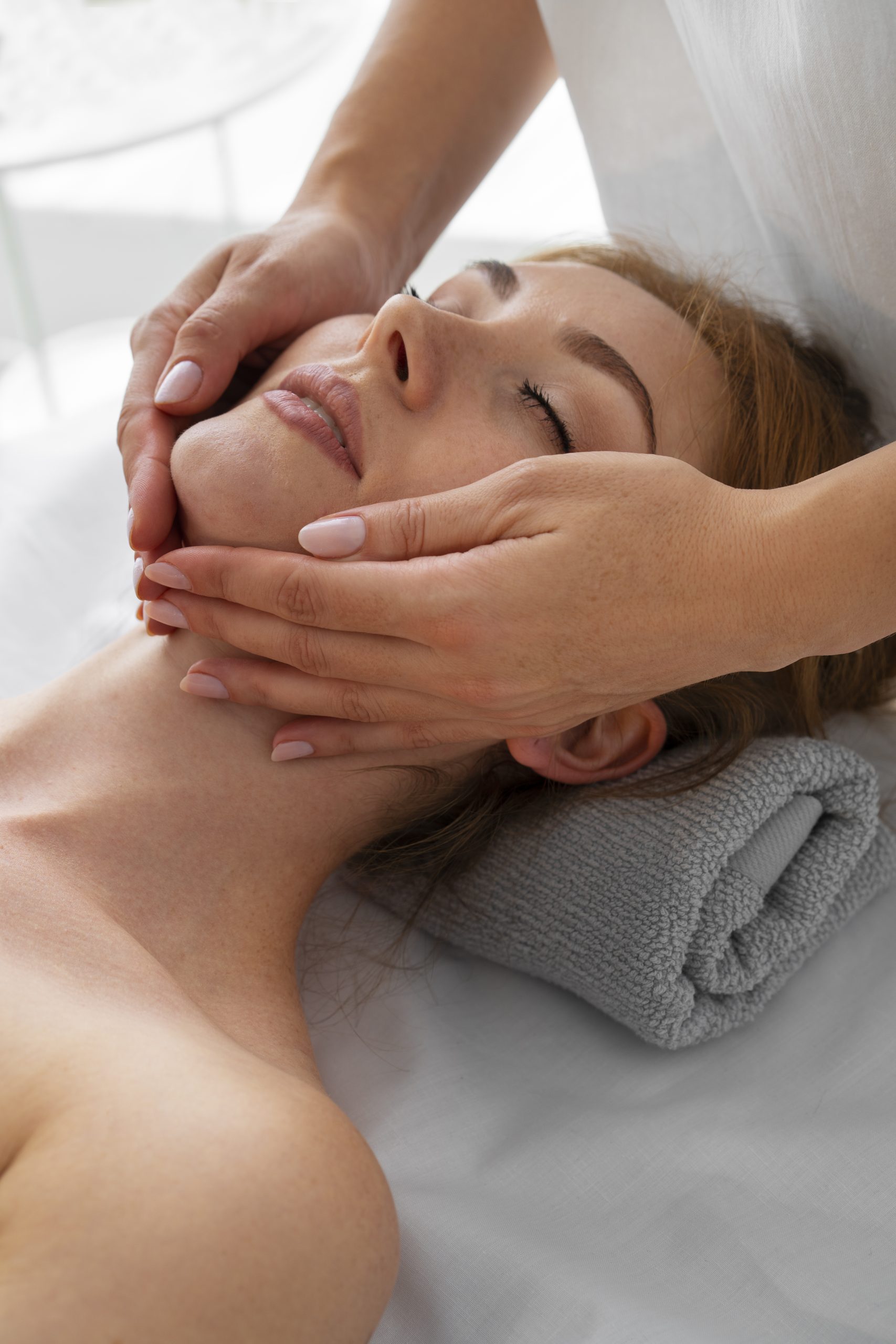 A woman getting a relaxing facial massage from a masseuse